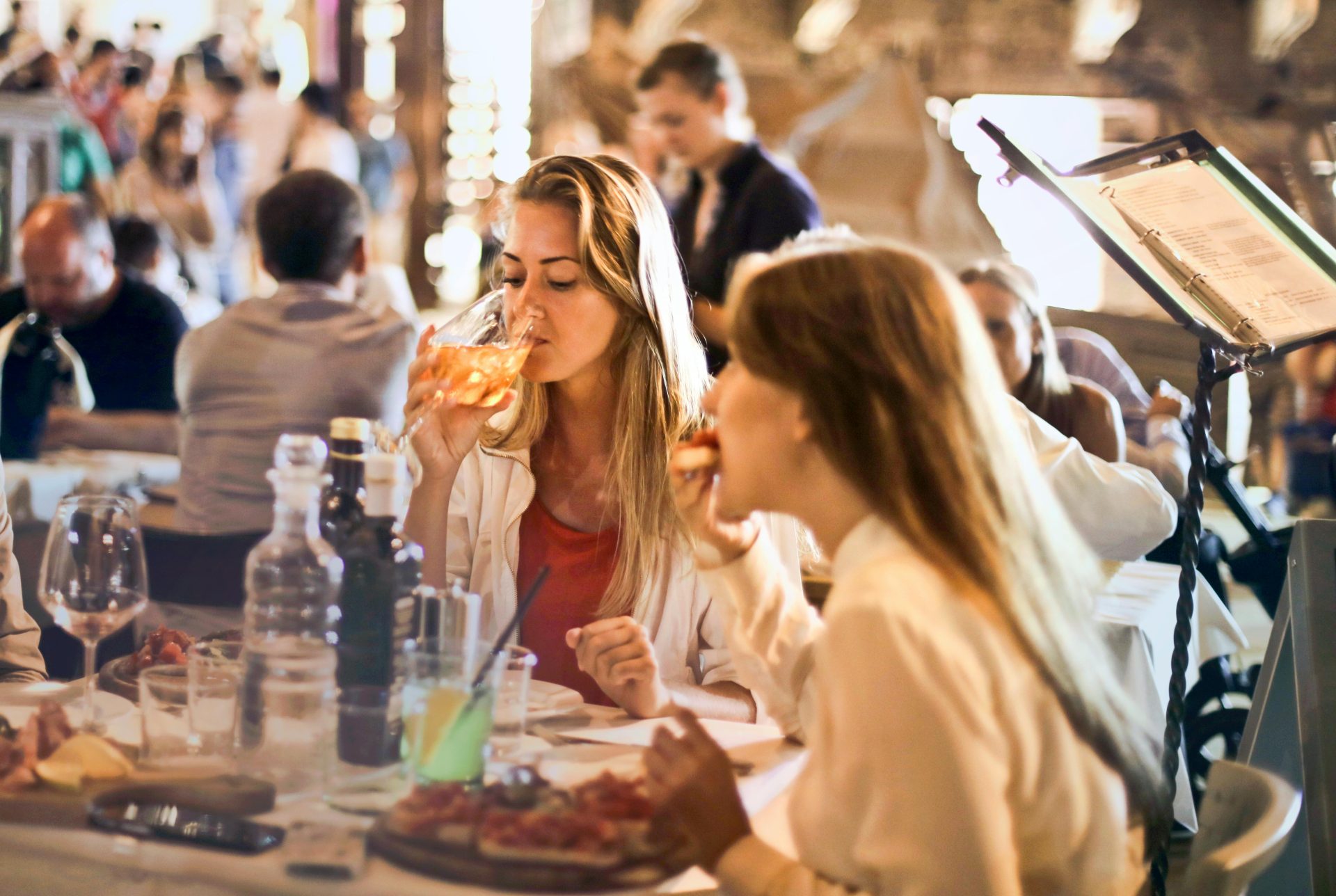 Amigos cenando en un acogedor restaurante italiano, disfrutando de bebidas y comida en un ambiente animado.